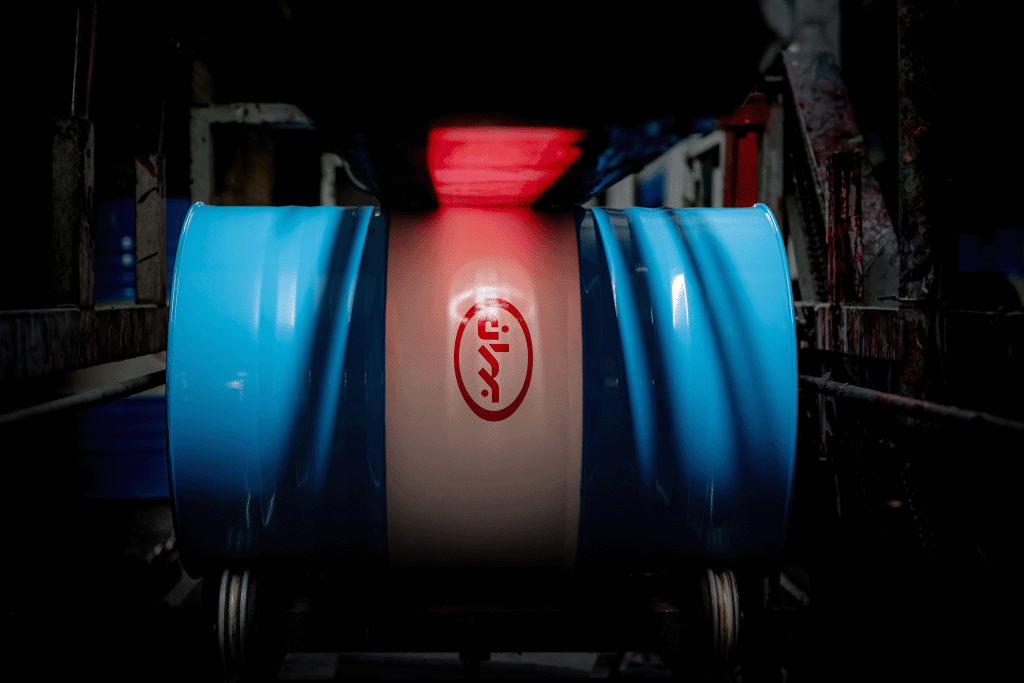 یک بشکه فلزی به رنگ آبی و سفید در مرحله تولید قسمت چاپ روی بدنه بشکه